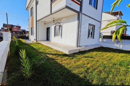 una casa blanca con un patio de hierba delante de ella en Cheerful villa in Kocaali 80 m from sea en Yukarı Kocaali
