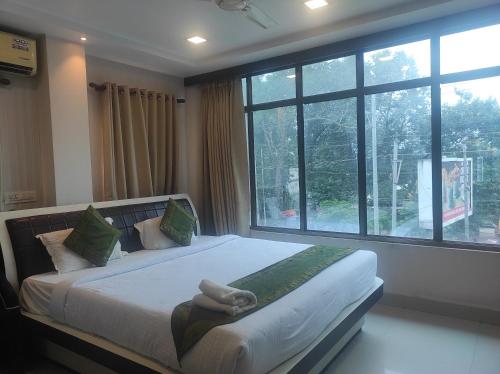 a bedroom with a large bed with a large window at Hotel Rudraksh- Near VIP Airport Guwahati in Guwahati