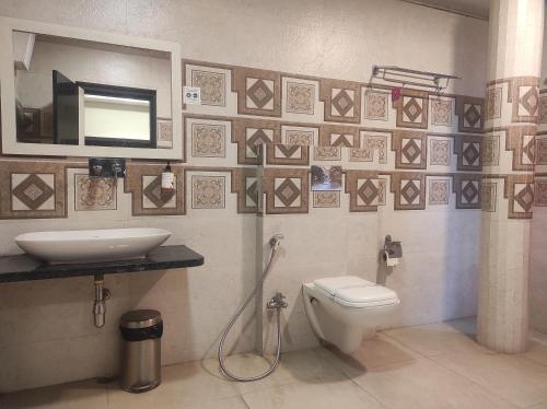 bagno con lavandino, servizi igienici e specchio di Hotel Rudraksh- Near VIP Airport Guwahati a Guwahati