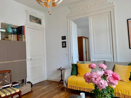 - un salon avec un canapé jaune et des fleurs roses dans l'établissement Persévérance, à Dinard