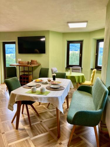 a living room with a table and green chairs at Penzion Na Výsluní České Švýcarsko in Dolní Podluží