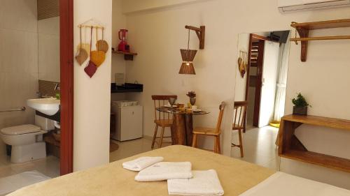 een kamer met een tafel en een badkamer met een wastafel bij Suítes Jardins de Flecheiras in Flecheiras