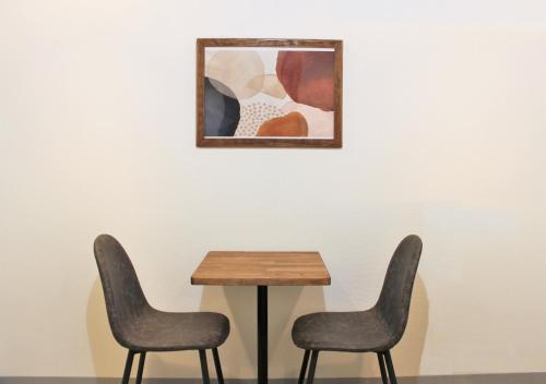 two chairs and a table in front of a painting at Apartment Hotel Hakata in Fukuoka