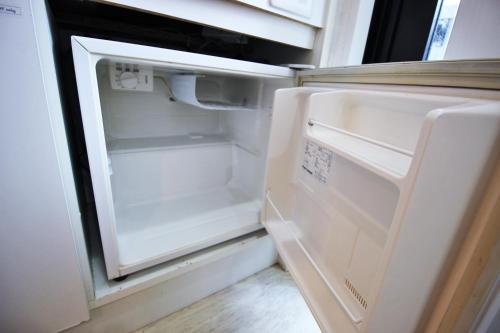 an empty refrigerator with its door open in a kitchen at Apartment Hotel Hakata in Fukuoka