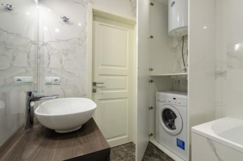 y baño blanco con lavabo y lavadora. en Central Park cozy apartments, en Kiev