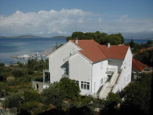 a white house with a red roof next to the water at Apartments by the sea Zlarin - 14025 in Zlarin