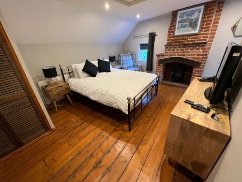 una camera con un letto in una stanza con camino di 4 Bedroom townhouse on one of the oldest streets a Wymondham