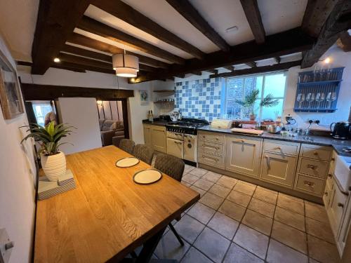 a kitchen with a wooden table with chairs and a refrigerator at 4 Bedroom townhouse on one of the oldest streets in Wymondham
