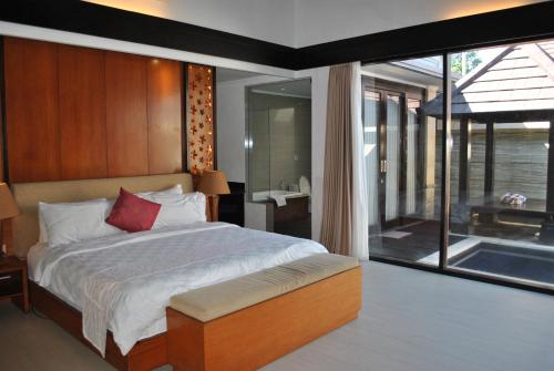 a bedroom with a large bed and a large window at Room in Villa - Kori Maharani Villas - One Bedroom Villa with Private Pool 4 in Siyut