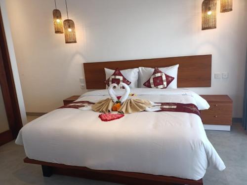 a bedroom with a large bed with a stuffed animal on it at The Kd Suites & Coffee Shop in Munggu