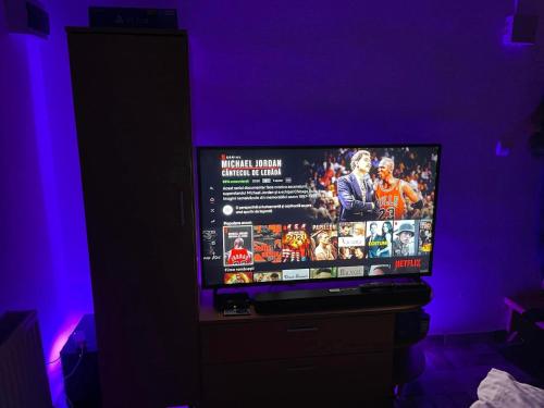 a flat screen tv sitting in a room with purple lighting at Vila Enjoy in Văliug