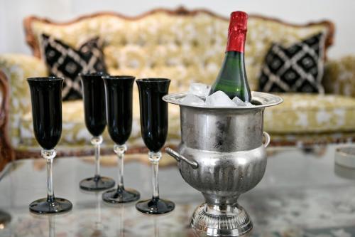 a wine bottle in a bucket on a table with four wine glasses at Le Petit Bijou Boutique Apartments - Solar Power in Franschhoek