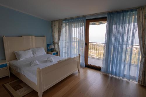 a bedroom with a white bed and a large window at Villa Sveta in Petrovac na Moru