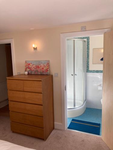 a bathroom with a wooden dresser and a shower at 1 Coach House Mews - Matlock Bath in Matlock Bank