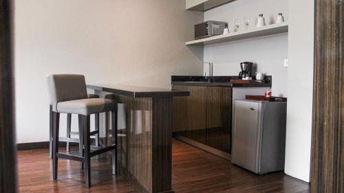 a kitchen with a bar with a chair and a refrigerator at Holiday Inn Bucaramanga Cacique by IHG in Bucaramanga
