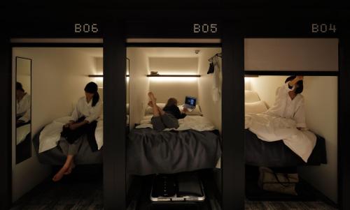 duas mulheres sentadas em camas num quarto de hotel em The Millennials Shibuya em Tóquio