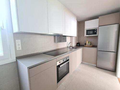 eine Küche mit weißen Schränken und einem Kühlschrank aus Edelstahl in der Unterkunft Apartamento Nicores Bidasoa in Irún