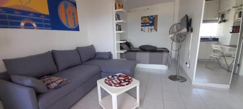Perla's House Studio with incredible sea view في بويرتو دي لا كروث: غرفة معيشة مع أريكة زرقاء وطاولة