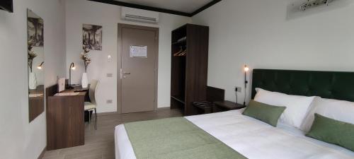 a bedroom with a bed with a green headboard and a desk at Suites Direzionale Carpi in Carpi