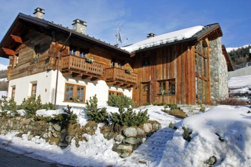 a large wooden house with a balcony in the snow at Livigno Chalets in Livigno