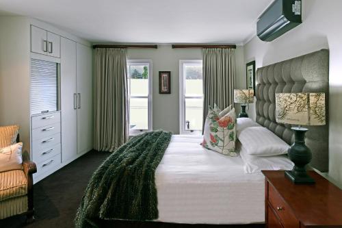 a bedroom with a large bed with a green blanket on it at Le Petit Bijou Boutique Apartments - Solar Power in Franschhoek
