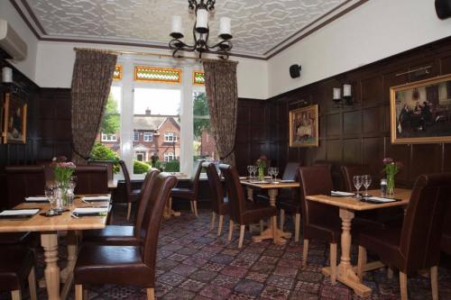 a restaurant with wooden tables and chairs and a window at Eskdale Lodge in Sale