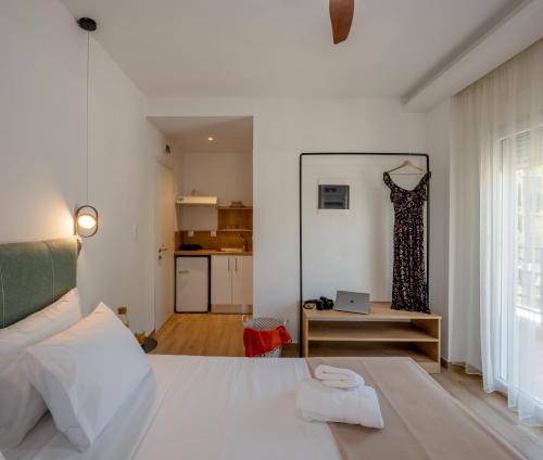 um quarto branco com uma cama e uma cozinha em Aiora Suites by Booking Kottas em Psakoudia