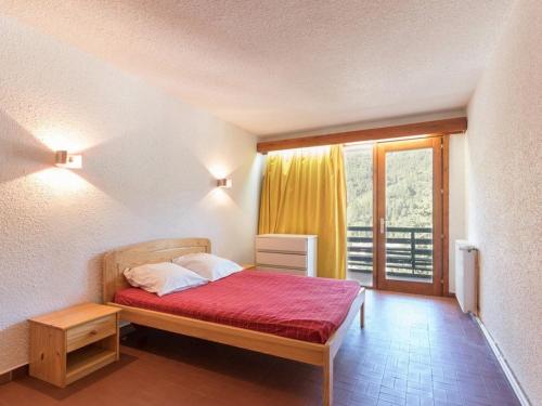 une chambre avec un lit avec une couverture rouge et une fenêtre dans l'établissement Charmant appart 4 pers, parking, proche pistes - Chantemerle, Serre-Chevalier - FR-1-330E-26, à Saint-Chaffrey