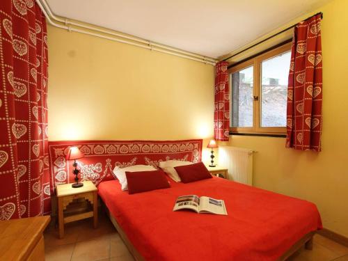- une chambre avec un lit rouge et un livre dans l'établissement Charmant T2 avec coin montagne, proche pistes et commerces, 6 couchages, terrasse, Serre Chevalier - FR-1-330E-104, à Saint-Chaffrey