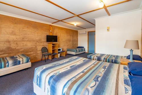 Cette chambre comprend deux lits et une télévision. dans l'établissement Great Western Motel Norseman, à Norseman