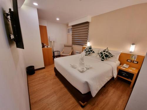 a hotel room with a large white bed with a table at ALVEA HOTEL in Puerto Princesa City