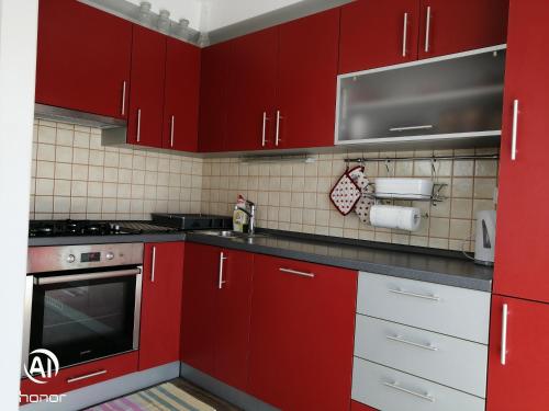 uma cozinha vermelha com armários e electrodomésticos brancos em Family apartment B&B em Biograd na Moru