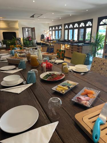 L'Insoupçonnée Saint Rémy de Provence by A Pinch Of Soul في Noves: طاولة خشبية طويلة عليها صحون وطعام