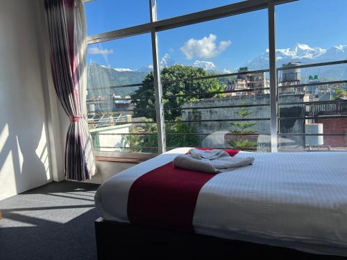 a bedroom with a bed and a large window at Pokhara Backpackers Hostel in Pokhara