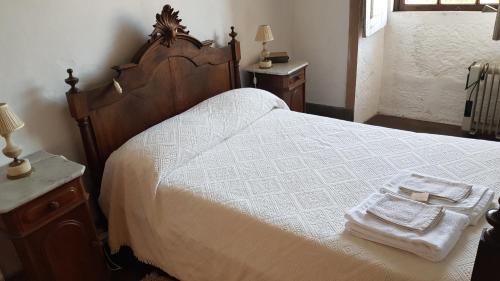 a bedroom with a large white bed with a wooden frame at Casa Dos Strecht's in Castelo de Paiva