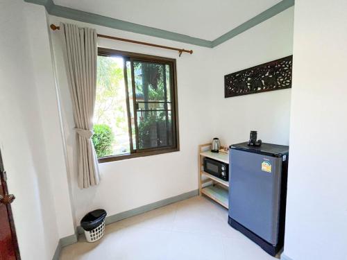 a kitchen with a blue refrigerator and a window at TropiCoco Beach Resort Koh Phangan in Haad Yao