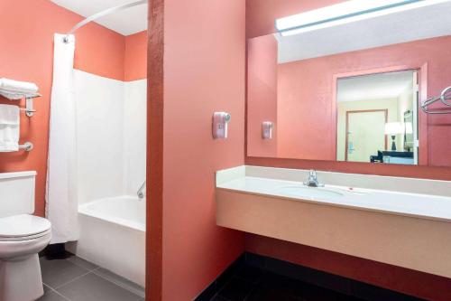 ein Badezimmer mit einem Waschbecken, einem WC und einem Spiegel in der Unterkunft Travelodge by Wyndham Richmond IN in Richmond