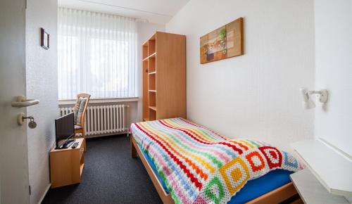 ein Schlafzimmer mit einem Bett mit einer bunten Decke in der Unterkunft Hotel Schwung in Bocholt
