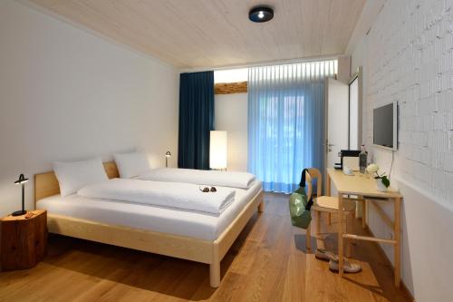 Dormitorio con cama, escritorio y TV en Gasthof zum weissen Rössli, en Erschwil