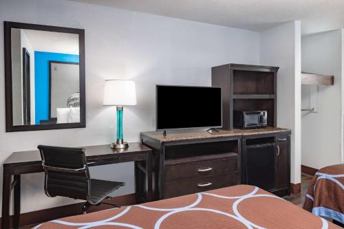 a hotel room with a desk with a computer and a mirror at Super 8 by Wyndham Pensacola in Pensacola