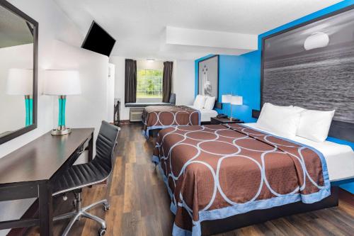 a hotel room with two beds and a desk at Super 8 by Wyndham Pensacola in Pensacola