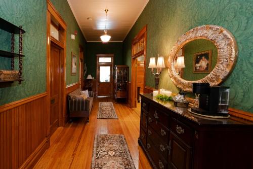 um corredor com paredes verdes, um espelho e uma cómoda em Captain Henderson House em Arkadelphia