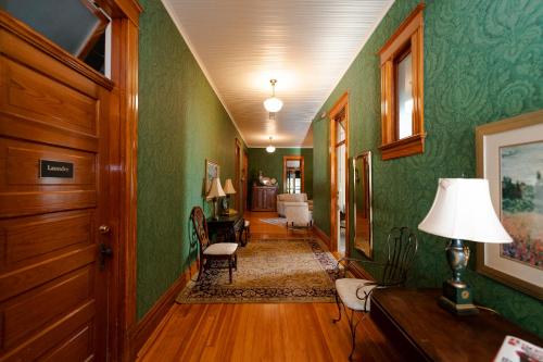 um corredor de uma casa com paredes verdes e um candeeiro em Captain Henderson House em Arkadelphia