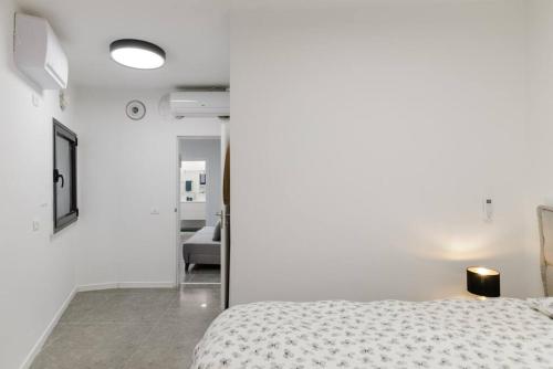 ein weißes Schlafzimmer mit einem Bett und einem Flur in der Unterkunft Unique Urban Villa - Live Local with Style in Tel Aviv