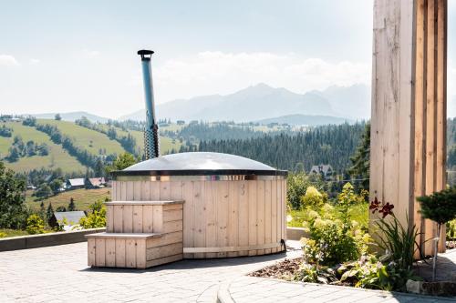 Sielsko Anielsko Tatry Jacuzzi & Sauna في بيالكا تاترزانسكا: مبنى صغير على فناء مع جبال في الخلفية