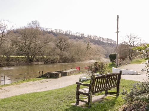 a park bench sitting in the grass next to a river at Steel Works Farm in Ross on Wye