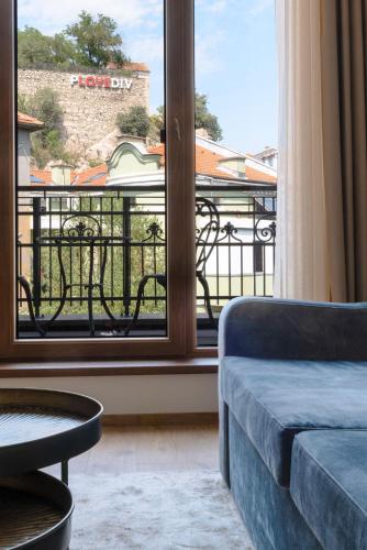 a living room with a couch and a large window at Villa Flavia Heritage Boutique Hotel in Plovdiv