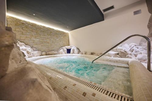 a jacuzzi tub in a room with a rock wall at Hotel Umag Plava Laguna in Umag