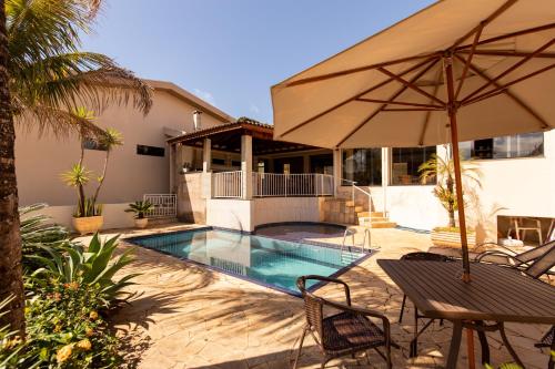 une maison avec une piscine et un parasol dans l'établissement Hospedaria do Lago, à Espirito Santo Do Pinhal