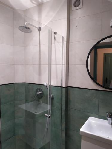 a bathroom with a shower with a sink and a mirror at Pokoje Nad Arkadami in Zamość
